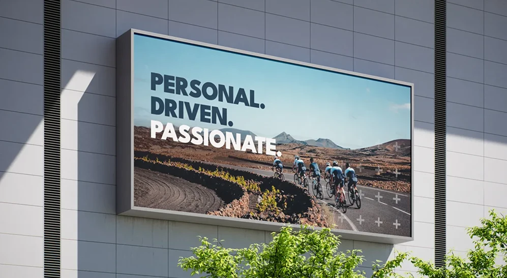 Billboard met de slogan Personal. Driven. Passionate. en een groep wielrenners